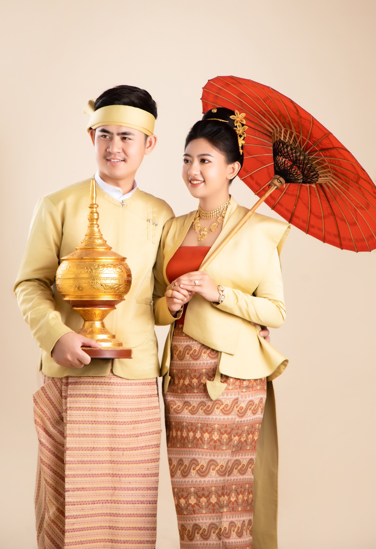 Traditional Myanmar couple with red parasol and golden heirloom